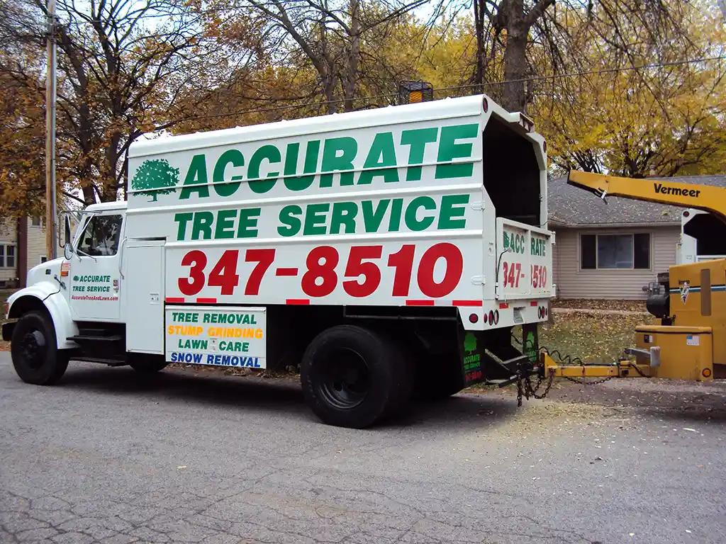 Accurate Tree Services truck parked in front a residential property with a wood chipper