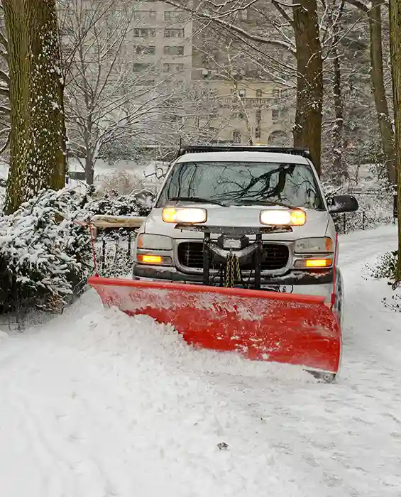 Truck with snow plow attached clearing road of snow