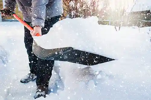 Worker shoveling snow in a residential area